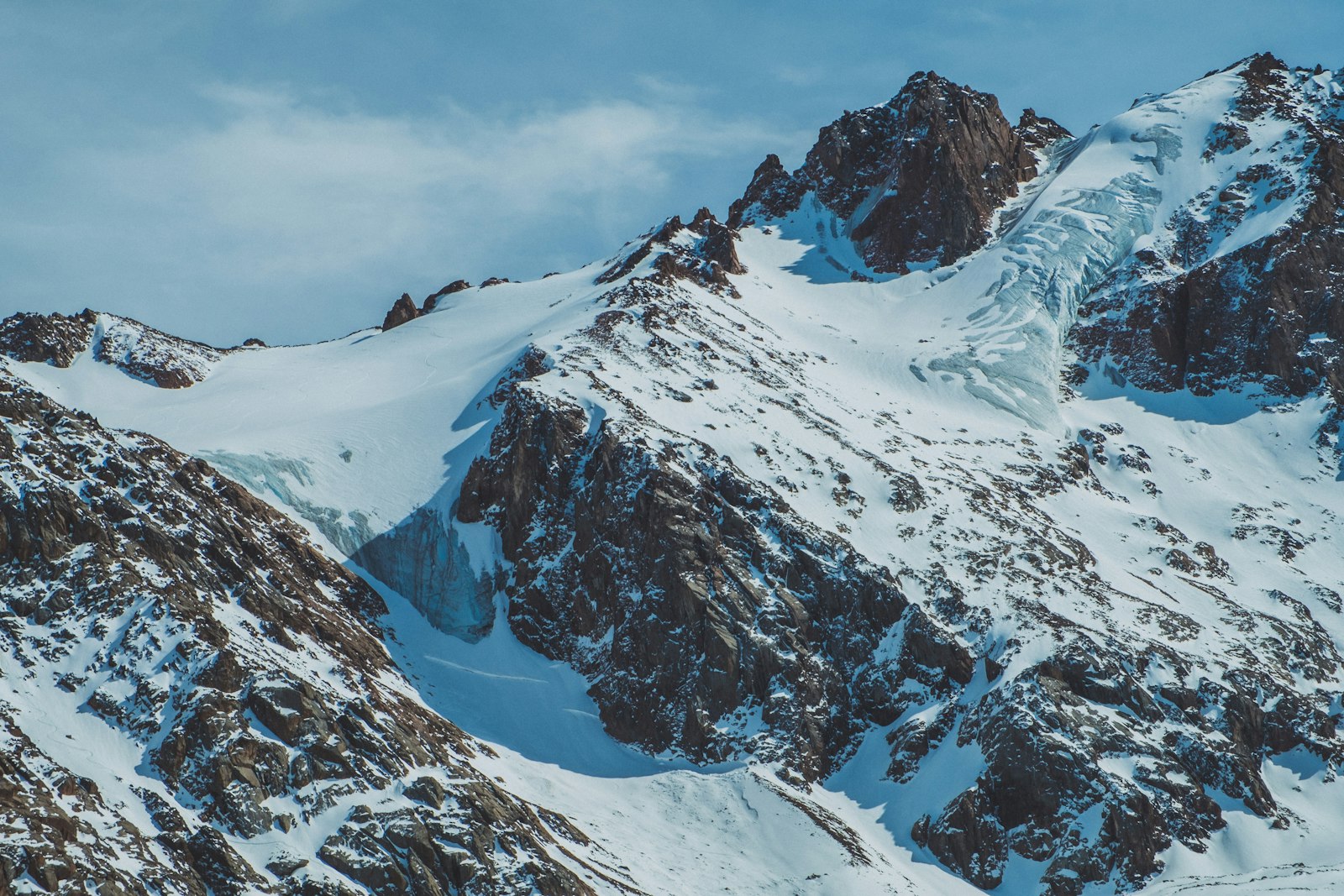 Snow-covered peaks and glacier above Shymbulak near Almaty under a blue sky